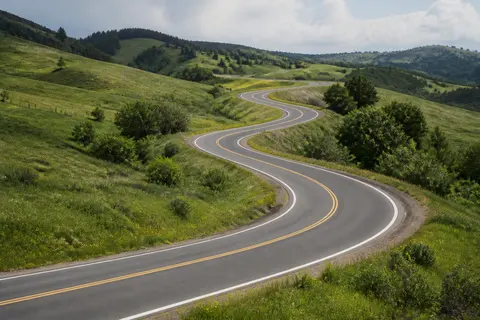 Minh họa cho “đường dẫn chữ S”: A winding road creates an S-curve into the hills.