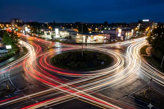 Long Exposure — Traffic light trails at a busy roundabout at night., kết quả Gemini.